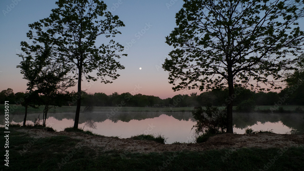 Full moon at daybreak, still waters with reflections Full moon at daybreak, still waters with reflections