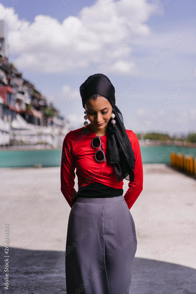 Fashion portrait of an Indian Asian lady wearing a traditional Indian clothing with hijab head scarf standing by the city during the day. She is tall,slim and fashionable.