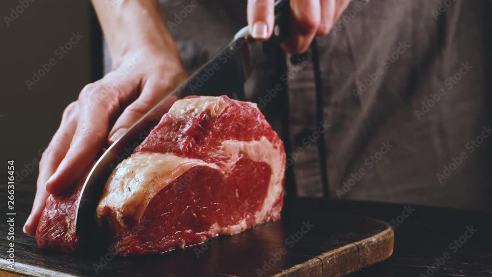 cook cuts raw meat for steaks