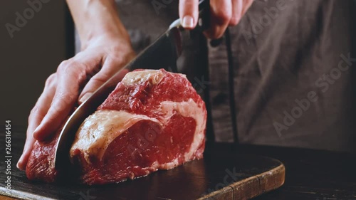 cook cuts raw meat for steaks