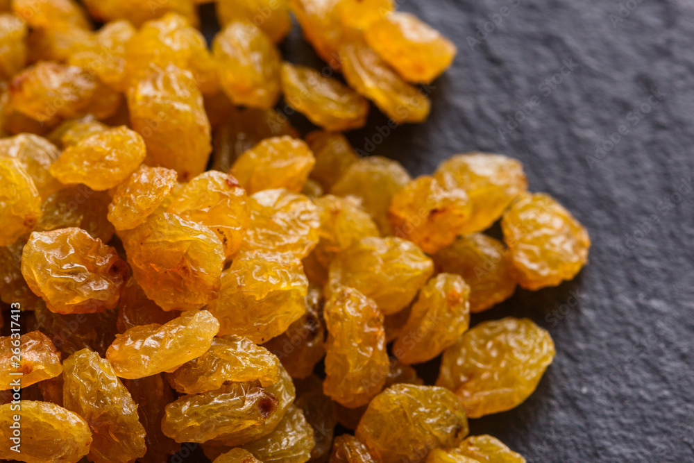 golden raisins on a dark stone background golden raisins on a dark stone background