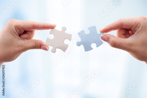 Human hands joining puzzle parts on background