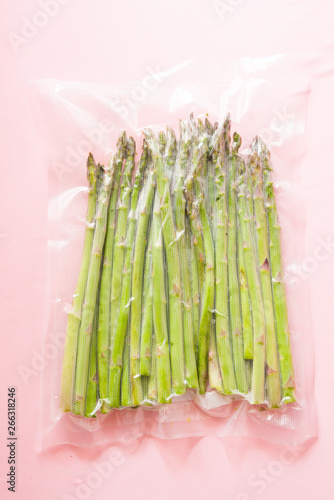 Vacuum sealed vegetables , asparagus, on a pink background top view, ready to be cooked with sous vide rooner photo