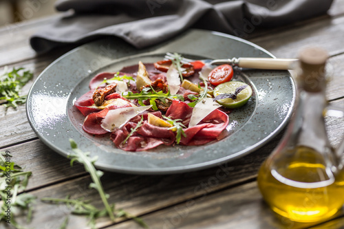 Принти на полотні Beef carpaccio on plate with dried tomatoes artichokes arugula and parmesan chee