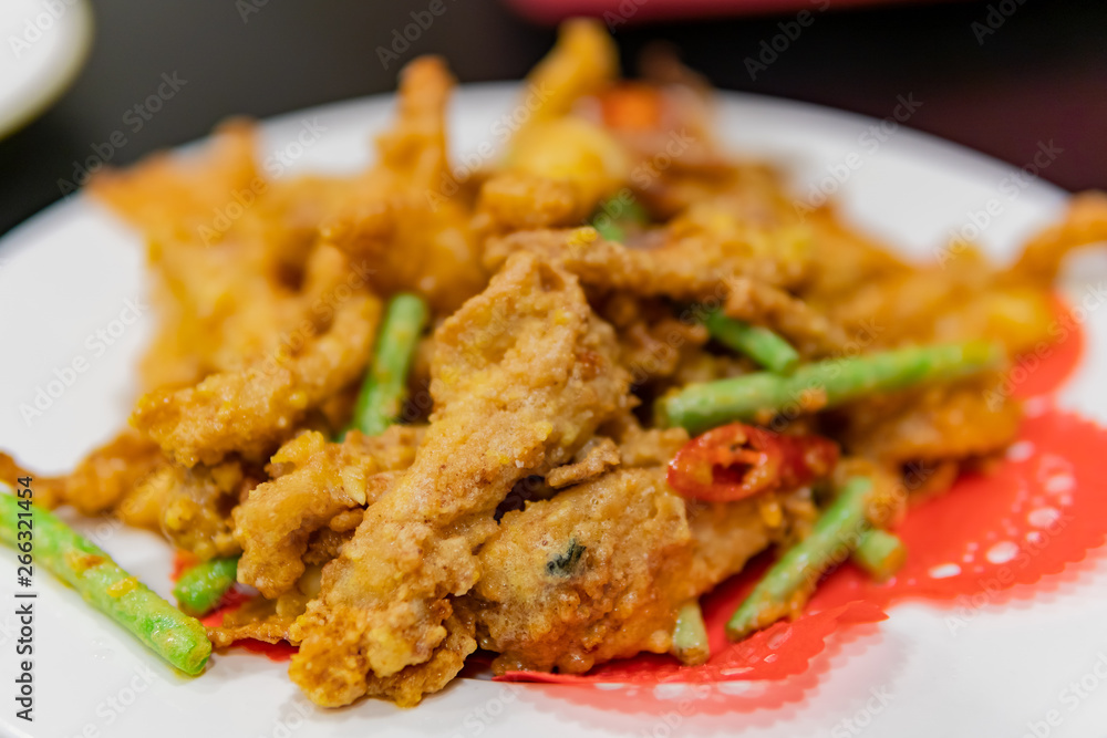 Close up shot of a dish of deep fried pork meat with salted duck egg and vegetable Close up shot of a dish of deep fried pork meat with salted duck egg and vegetable
