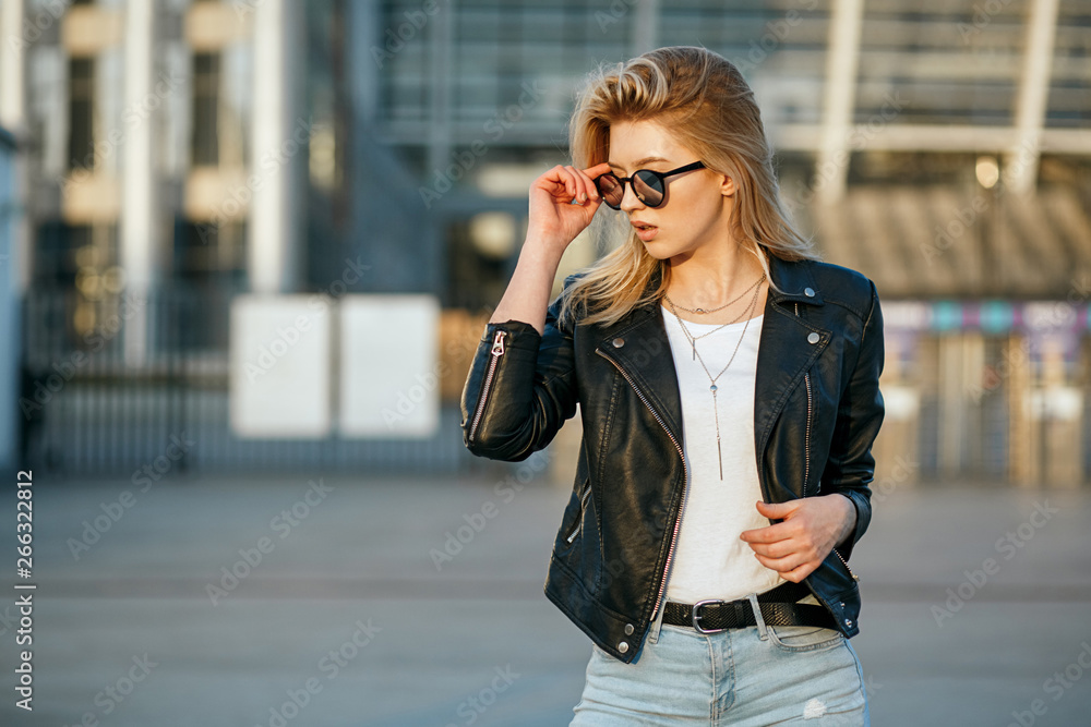 Fototapeta premium Lifestyle portrait of young wonderful woman wearing mirror sunglasses and leather jacket. Empty space