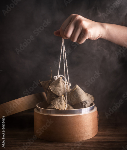 Zongzi, woman going to eat steamed rice dumpling on wood table, famous tasty food in dragon boat festival duanwu design concept, close up, copy space