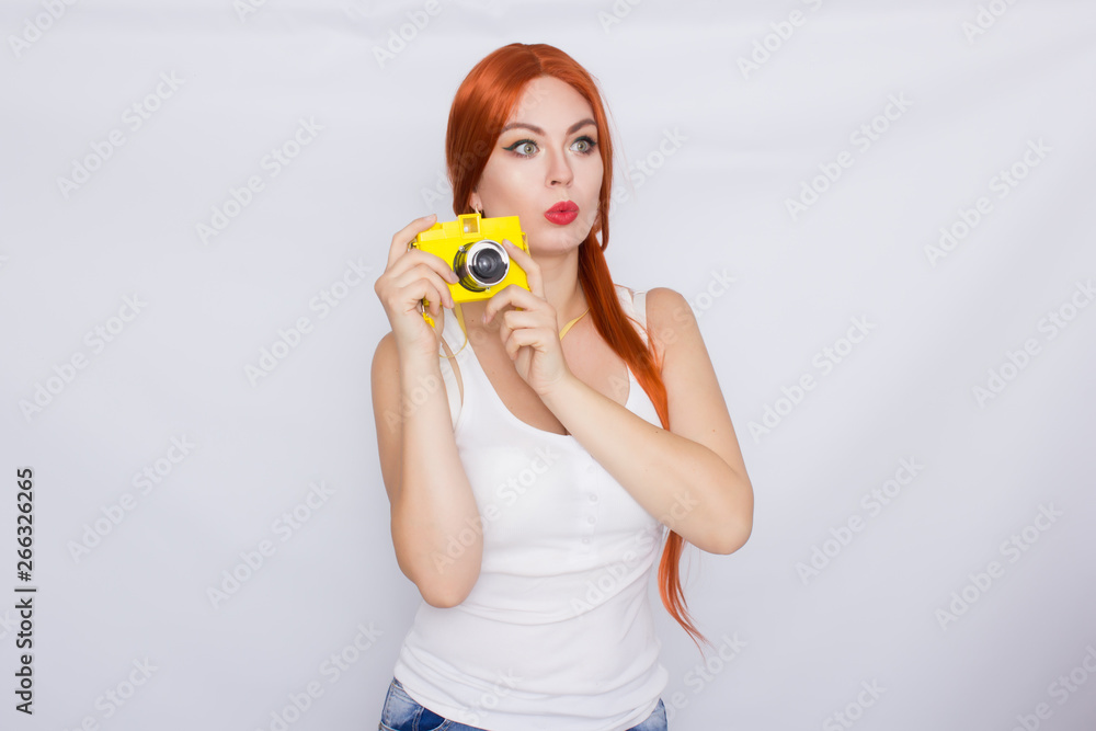 Redhead woman making photot and looking at yellow camera Redhead woman making photot and looking at yellow camera