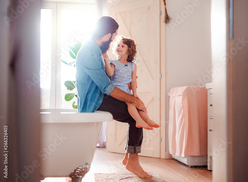 A small girl with young father in bathroom at home, talking. photo