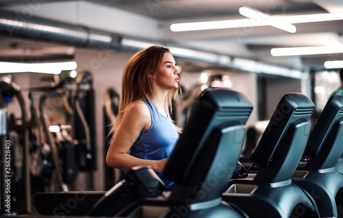 A portrait of young girl or woman doing cardio workout in a gym. © Halfpoint