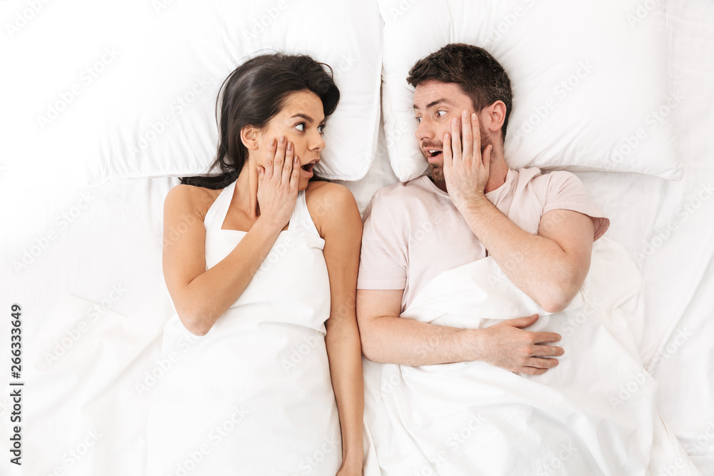 Shocked loving couple lies in bed under blanket. Shocked loving couple lies in bed under blanket.