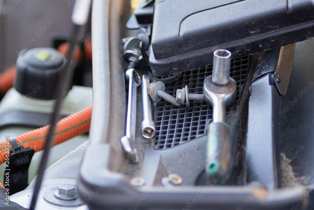 Professional mechanic tool lies on the windshield of an electric car Professional mechanic tool lies on the windshield of an electric car