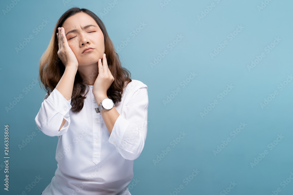 Woman has headache isolated over blue background Woman has headache isolated over blue background