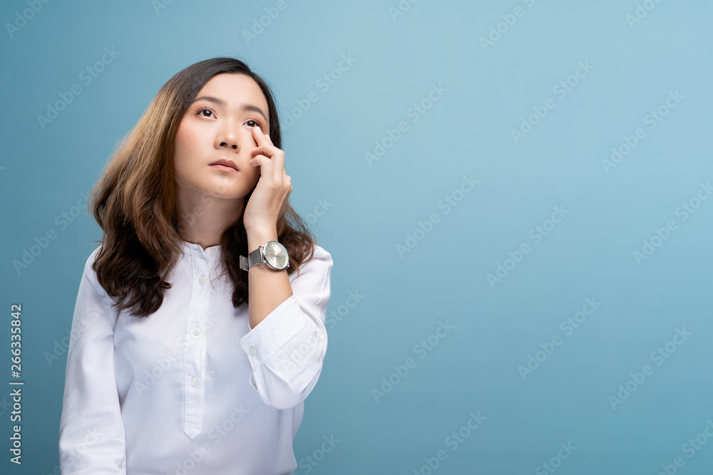 Woman has eyes pain isolated over blue background Woman has eyes pain isolated over blue background