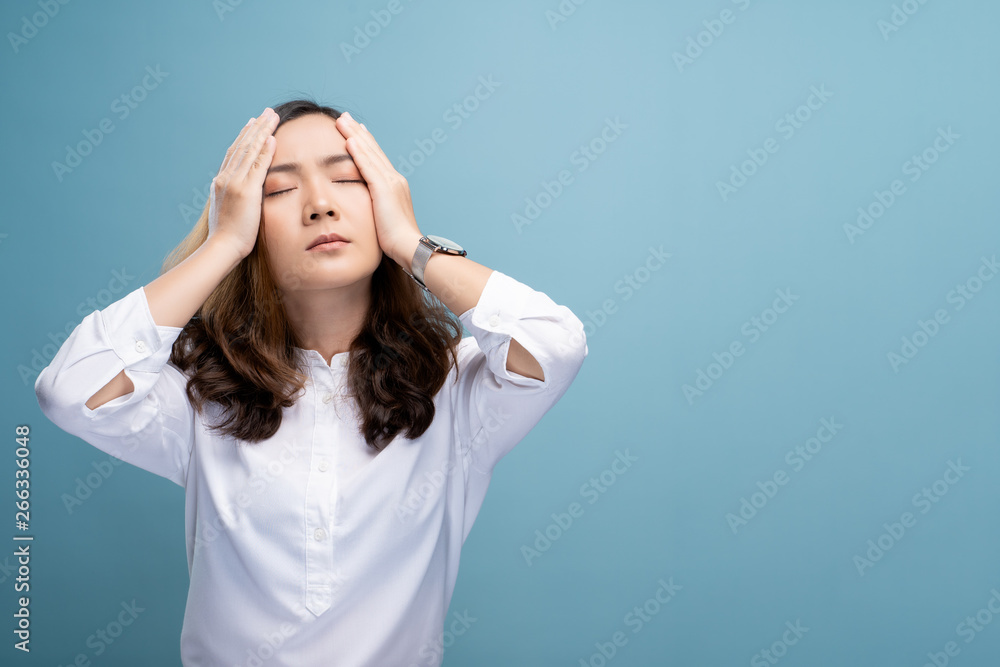 Woman has headache isolated over blue background Woman has headache isolated over blue background