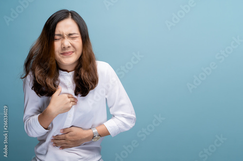 Woman has chest pain isolated over blue background photo