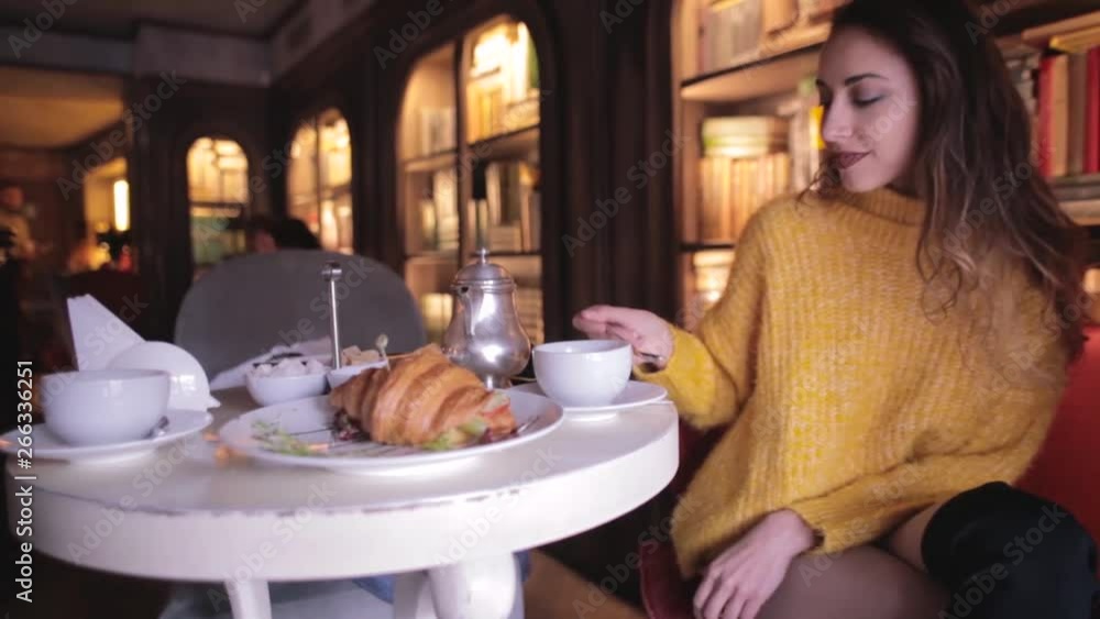 young pretty woman in yellow sweater having breakfast in cozy cafe and drinking tea. young pretty woman in yellow sweater having breakfast in cozy cafe and drinking tea.