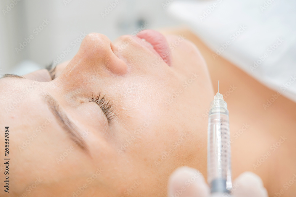 Naklejka premium Cosmetologist making mesotherapy injection. Syringe and needle injecting botox. Female patient, woman is getting botox procedure at beautician. Hardware cosmetology, face rejuvenation. Close up
