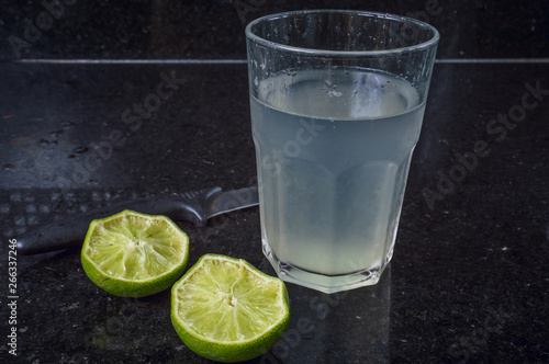 A glass of water and lemons against white background