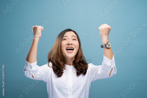 Obraz na plátně Happy woman make winning gesture isolated over blue background