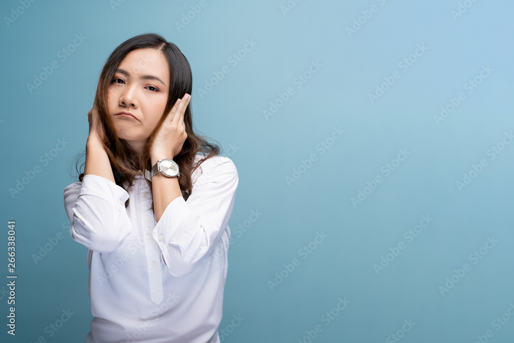 Woman covering her ears and standing isolated over blue background Woman covering her ears and standing isolated over blue background