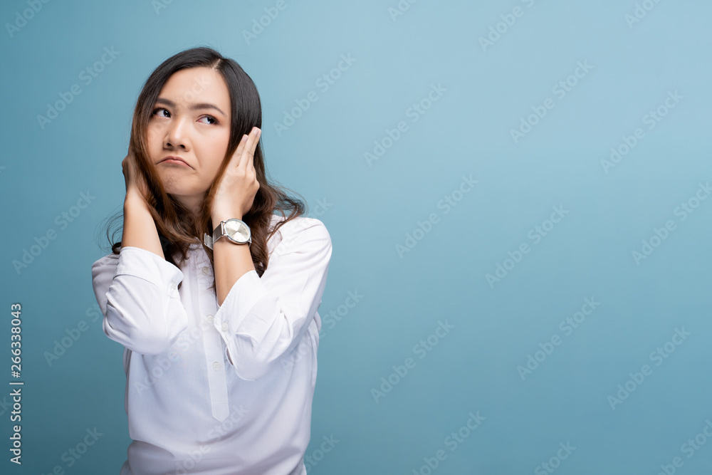 Woman covering her ears and standing isolated over blue background Woman covering her ears and standing isolated over blue background
