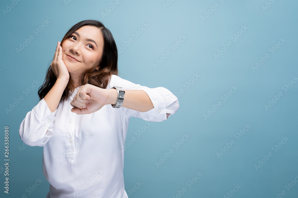 Happy woman holding hand with wrist watch isolated on a blue background Happy woman holding hand with wrist watch isolated on a blue background