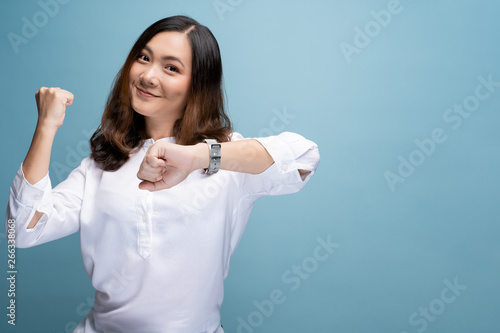 Happy woman holding hand with wrist watch isolated on a blue background