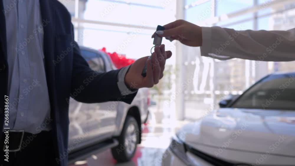 Auto business, hands of saleswoman give keys to customer owner of new car and shakes hands close-up during successful purchase in sales center Auto business, hands of saleswoman give keys to customer owner of new car and shakes hands close-up during successful purchase in sales center