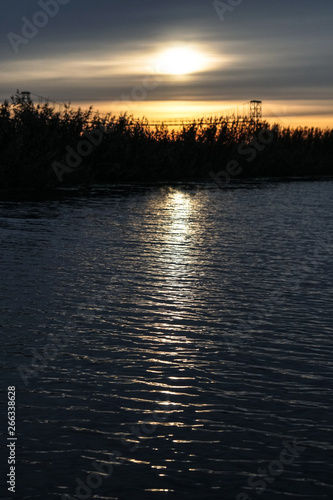 Sunset on the river, lake. The reflection of the sun in the water as in a mirror. Landscape background. Stock photo