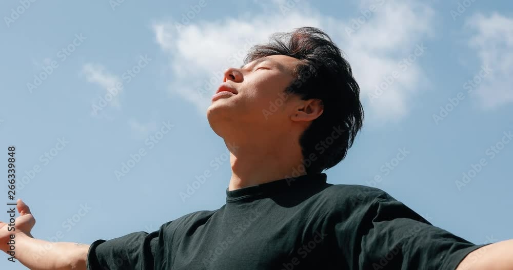 Man meditating on a freedom with raised hands, blue sky background Man meditating on a freedom with raised hands, blue sky background