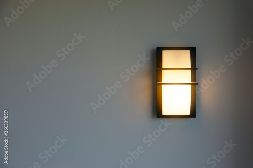 Close-up of a modern design of a wall mounted house lighting on white cement walls.