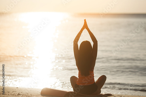 Young sporty woman doing yoga excercises on the beach