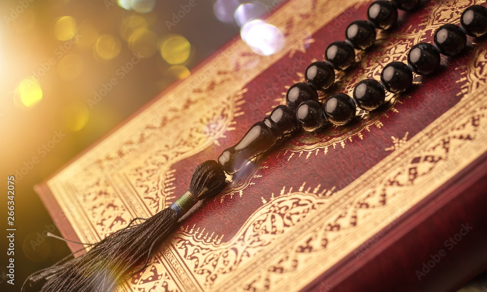 Islamic Book Koran with rosary on grey background Islamic Book Koran with rosary on grey background
