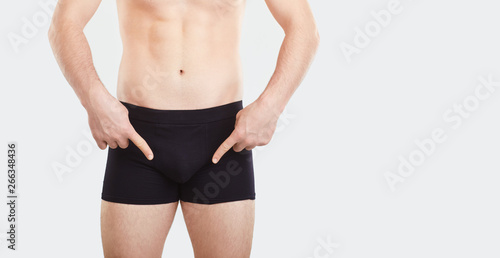 A man in underwear points his finger at the penis.