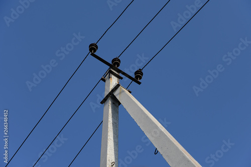 Electric post with blue sky background.