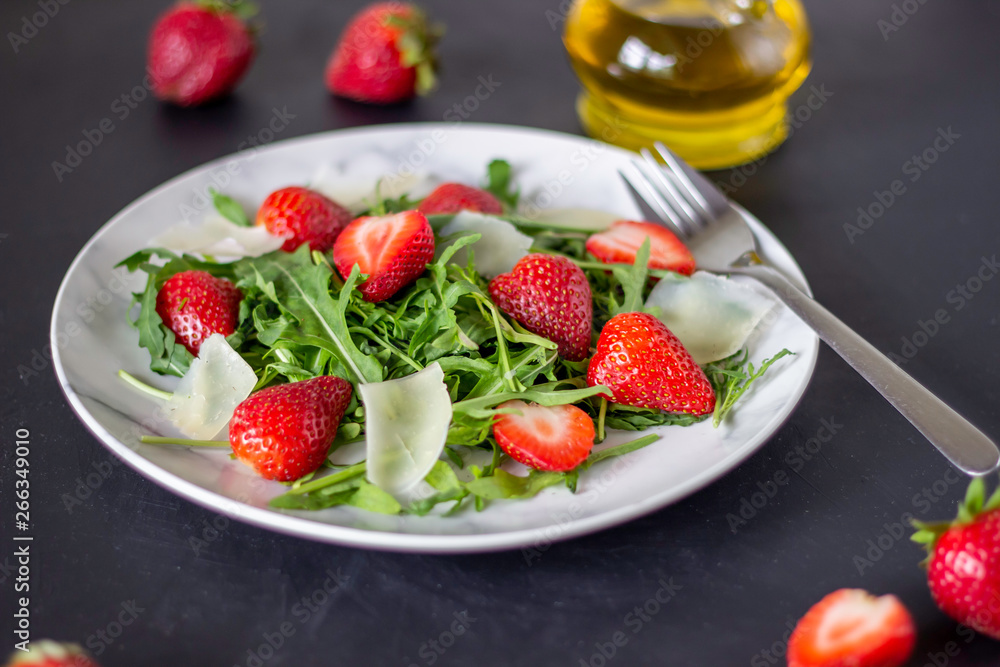 Salad of strawberries, arugula and cheese on a dark background. Dietary food. Salad of strawberries, arugula and cheese on a dark background. Dietary food.