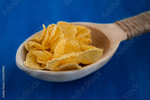  Cornflakes in a wooden spoon on a blue background