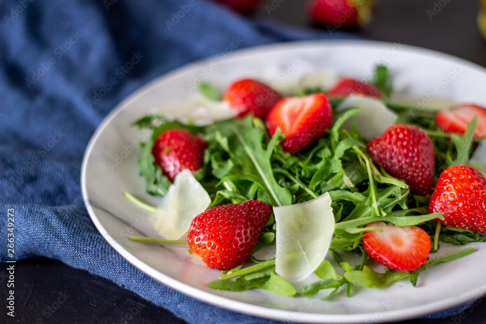 Salad of strawberries, arugula and cheese on a dark background. Dietary food. Salad of strawberries, arugula and cheese on a dark background. Dietary food.