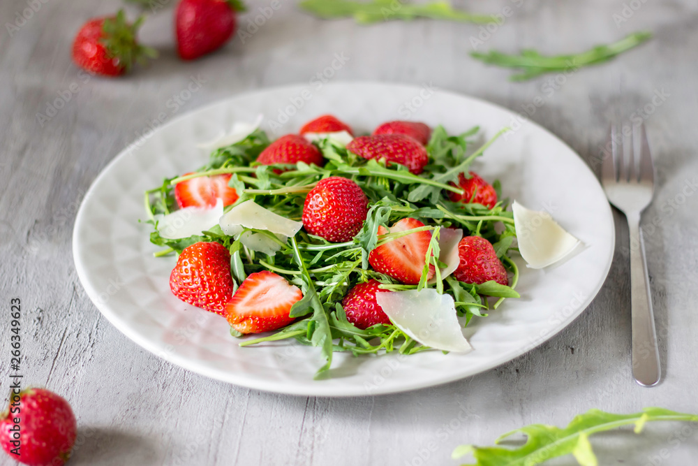 Salad of strawberries, arugula and cheese on a grey background. Dietary food. Salad of strawberries, arugula and cheese on a grey background. Dietary food.