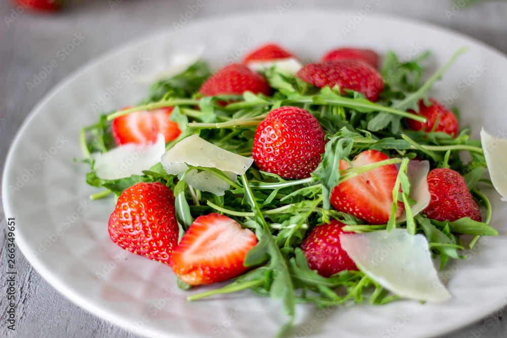 Salad of strawberries, arugula and cheese on a grey background. Dietary food. Salad of strawberries, arugula and cheese on a grey background. Dietary food.