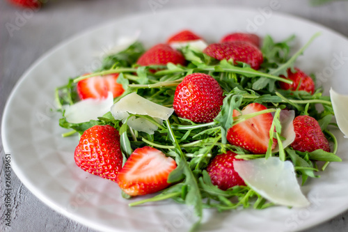 Salad of strawberries, arugula and cheese on a grey background. Dietary food.