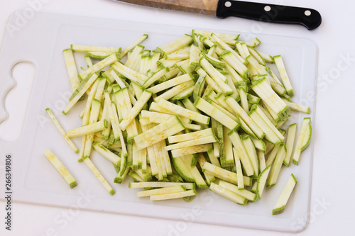 Zucchini sliced straws on a cutting board on a white background