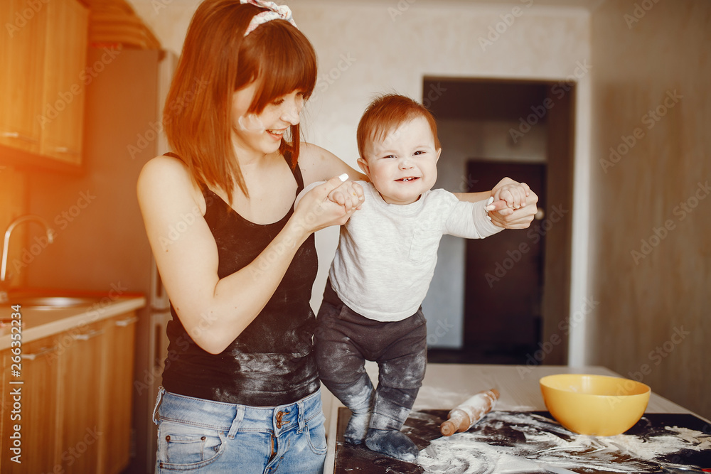 A young and beautiful mom is preparing food at home in the kitchen, along with her little son A young and beautiful mom is preparing food at home in the kitchen, along with her little son