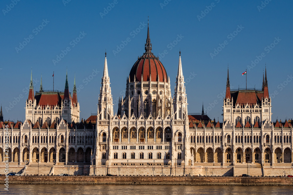 Hungary, Budapest: Famous Hungarian Parliament Building at sunny afternoon in the city center of the Hungarian capital with Donau Danube water, blue sky in background - travel architecture politics