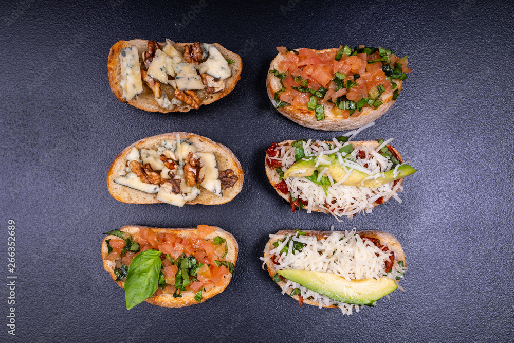 Appetizer bruschetta with cheese, honey, walnut and other ingredients on black background. Close-up. Italian food. Appetizer bruschetta with cheese, honey, walnut and other ingredients on black background. Close-up. Italian food.