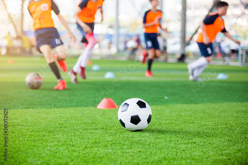soccer ball and marker cones on green artificial turf with blurry soccer team training © Koonsiri