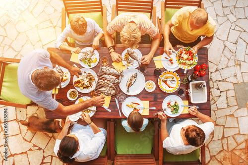 Big miltigeneration family dinner in process. Top view vertical image on table with food and hands photo