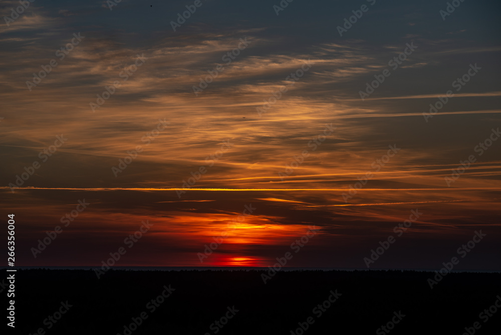 colorful sunset over the sea lake with dark red clouds