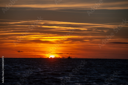 colorful sunset over the sea lake with dark red clouds